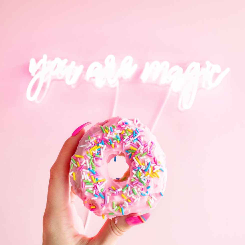 woman holding donut with sprinkles