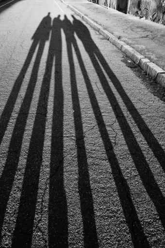 frightening shadow of unrecognizable friends on shabby road