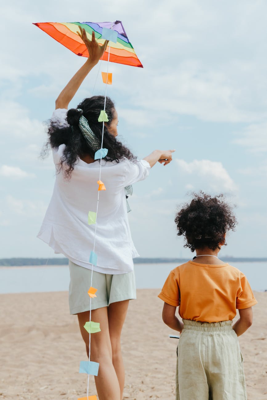 back view of mother and daughter playing at the beach