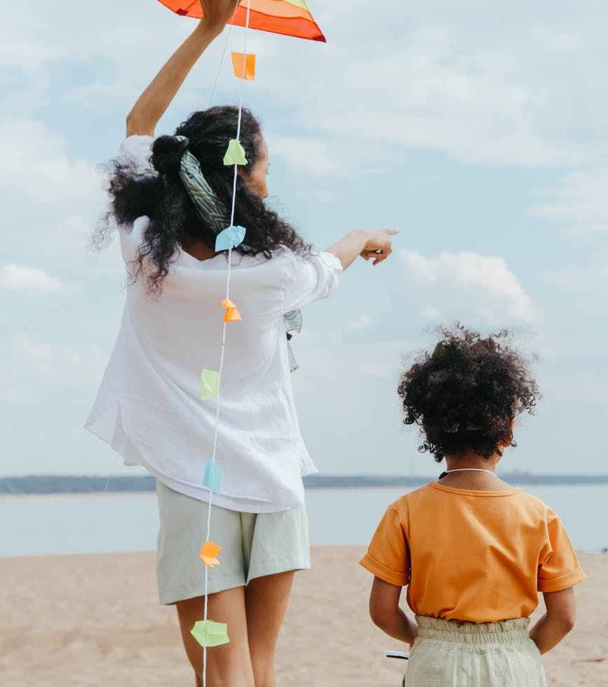 back view of mother and daughter playing at the beach