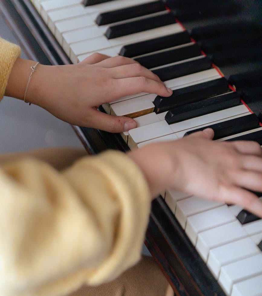 unrecognizable female musician playing melody on piano in room