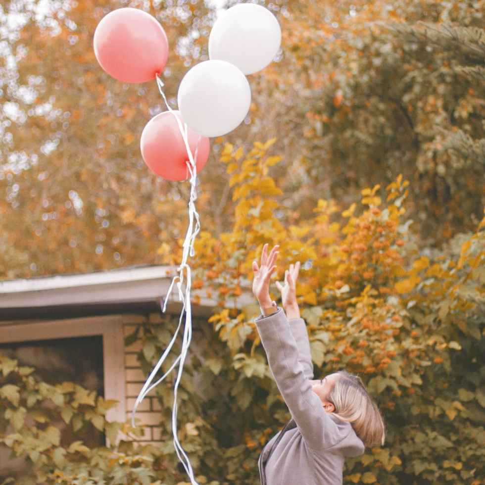 woman in gray jacket released balloons in the air